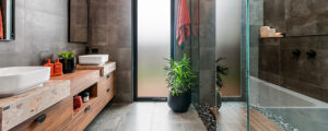 Ensuite with timber benchtops, grey tiles and large glass shower