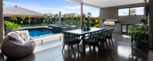 Photo of outdoor entertainment area with dining table and chairs, BBQ andseating, and swimming pool in the background