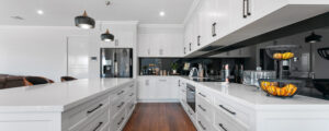 Modern white kitchen with black glass splashback and timber stools