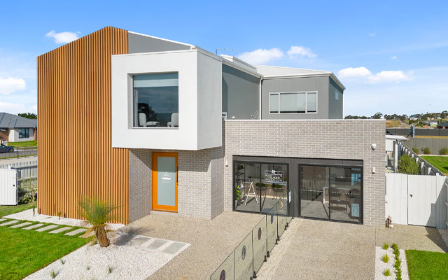Facade view of the 2 storey 'Olivia' Display Home in Traralgon, a grey rendered front with timber panels