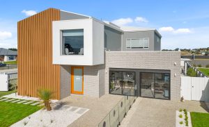 Facade view of the 2 storey 'Olivia' Display Home in Traralgon, a grey rendered front with timber panels