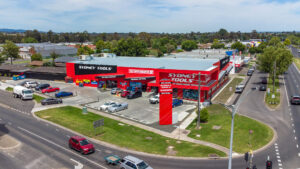 Photo of a large bright red industrial showroom and large carpark.