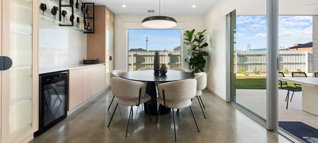 Photo of round dining table and 6 fabric covered chairs, timber cabinets on the side, in display home