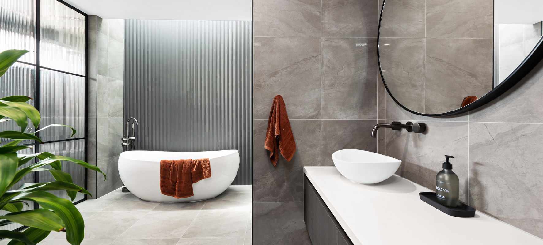 Photo of luxury bathroom with grey tiles, big white bathtub and white vanity