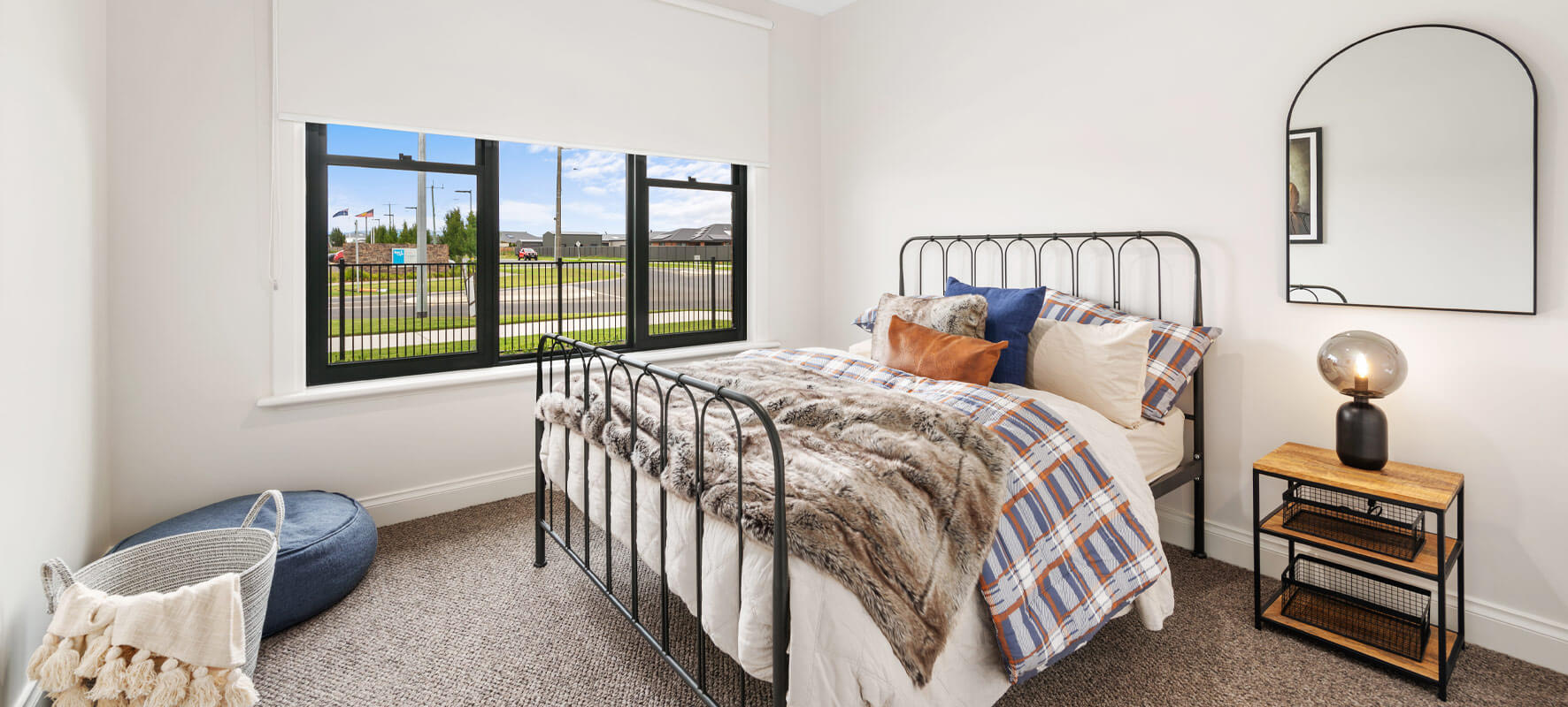 Photo of bedroom in Ranch style home showing black wought iron bed with country style bed linen.