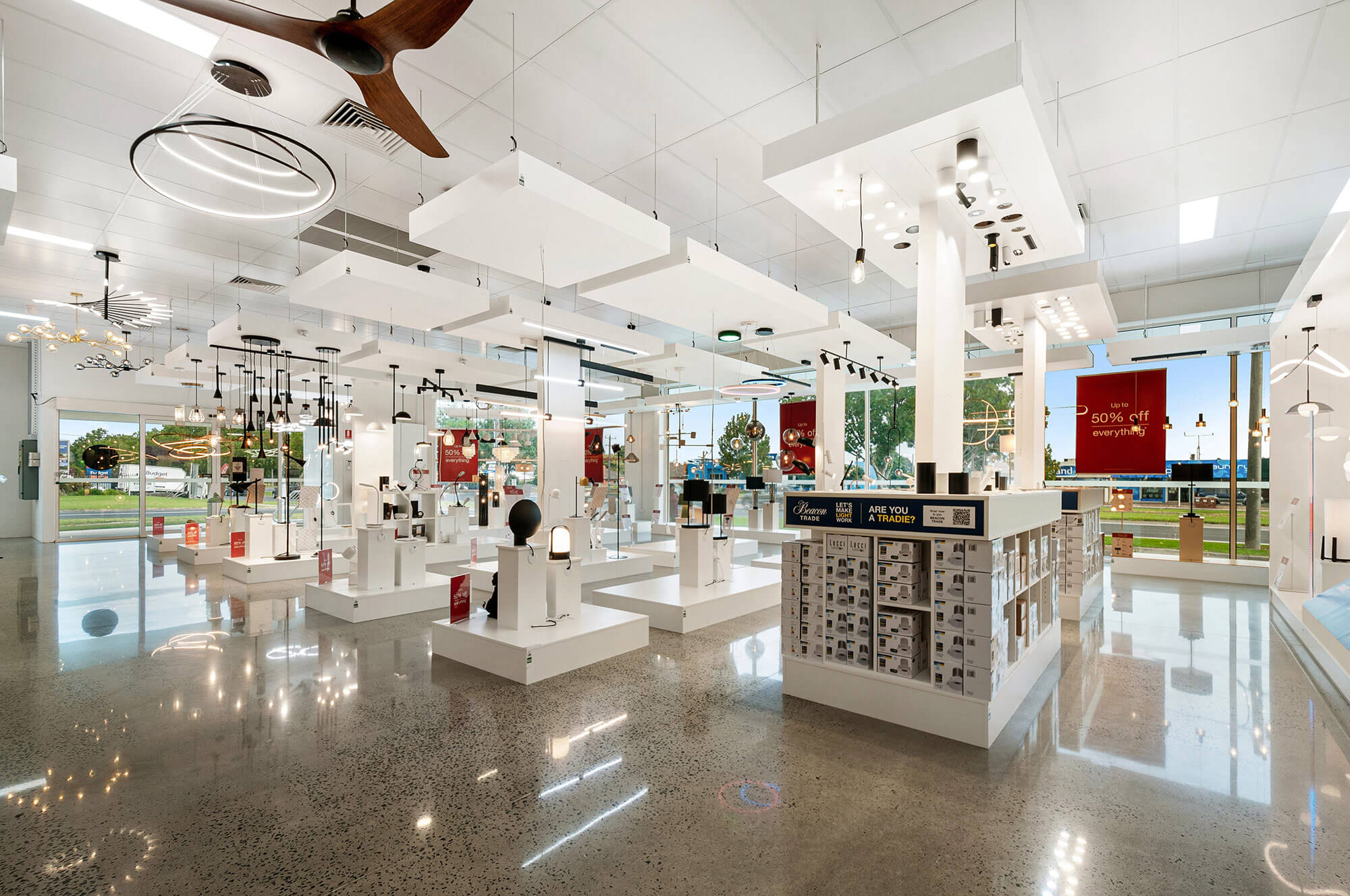 Photo of the interior of Beacon lighting store showing polished concrete floor, high white ceilings, and rows of various ceiling lights on display