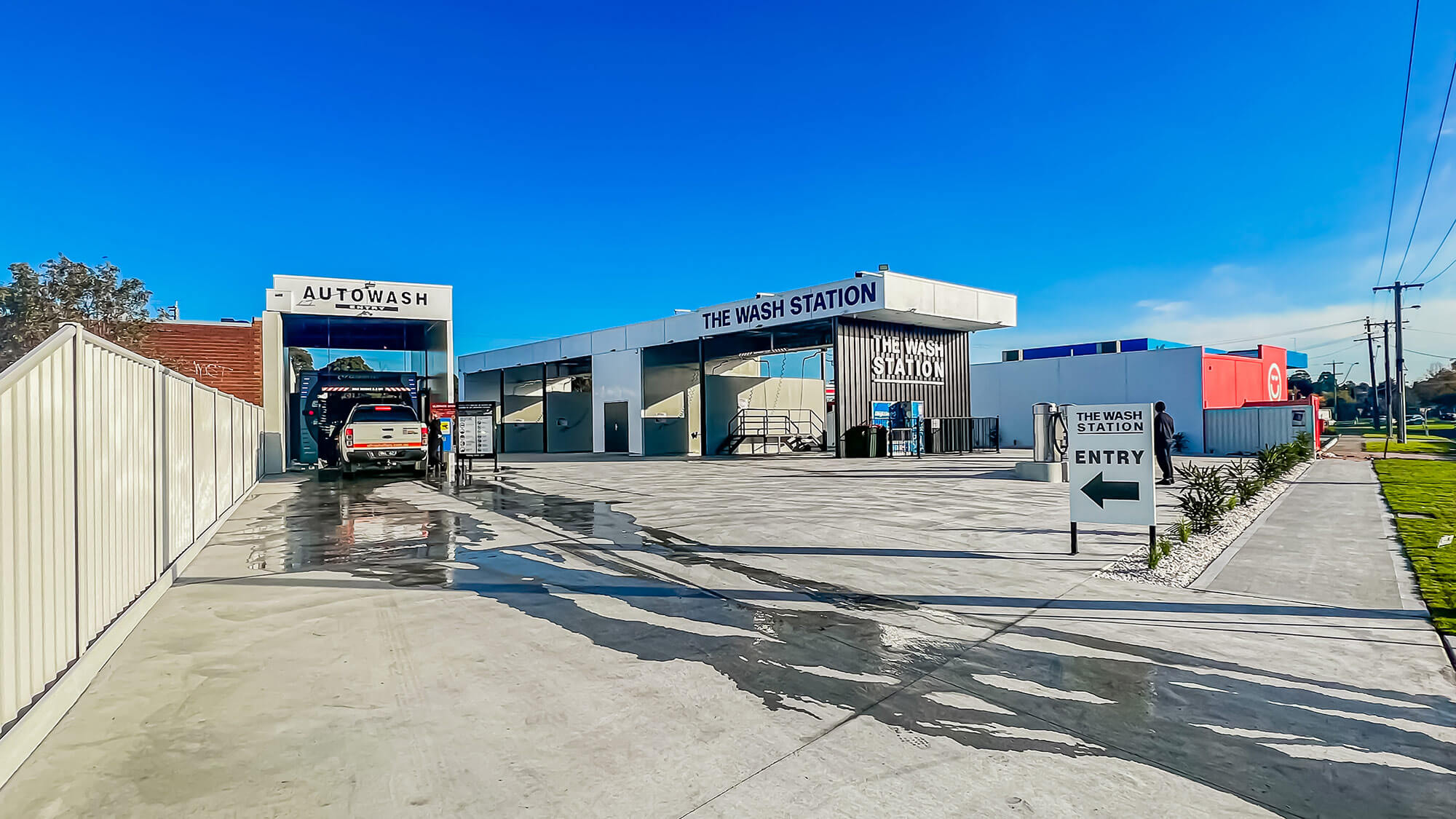 Photo of a modern new car wash business with driveway, auto car wash and bays for people to wash their own cars.