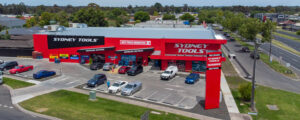 Aerial view of Sydney Tools building in bright red, on the corner of a busy intersection and with carpark