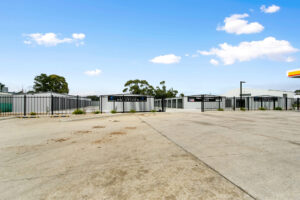 Photo of new storage shed facility, with rows of grey storage shed with black roller doors