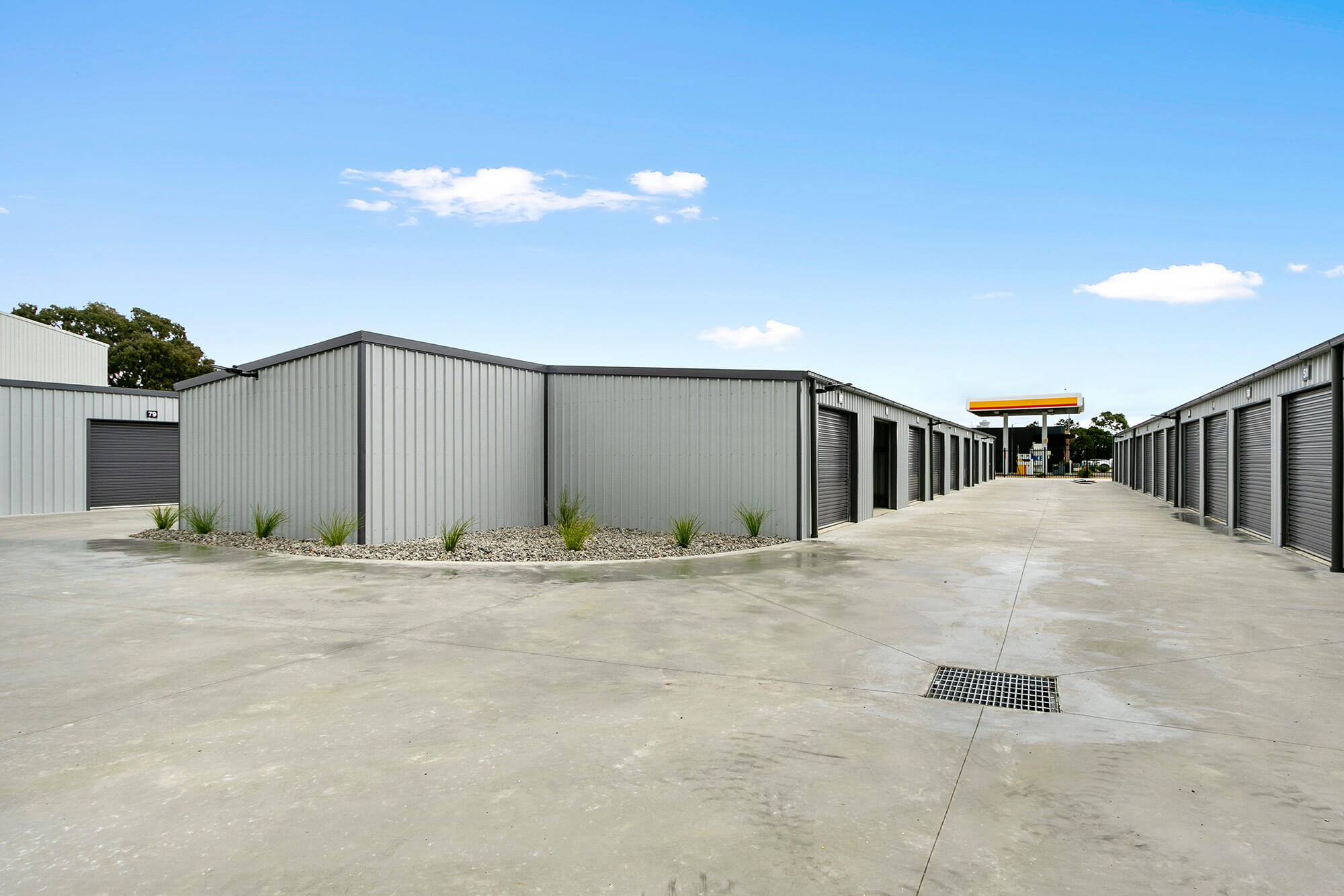 Photo of new storage shed facility, with rows of grey storage shed with black roller doors