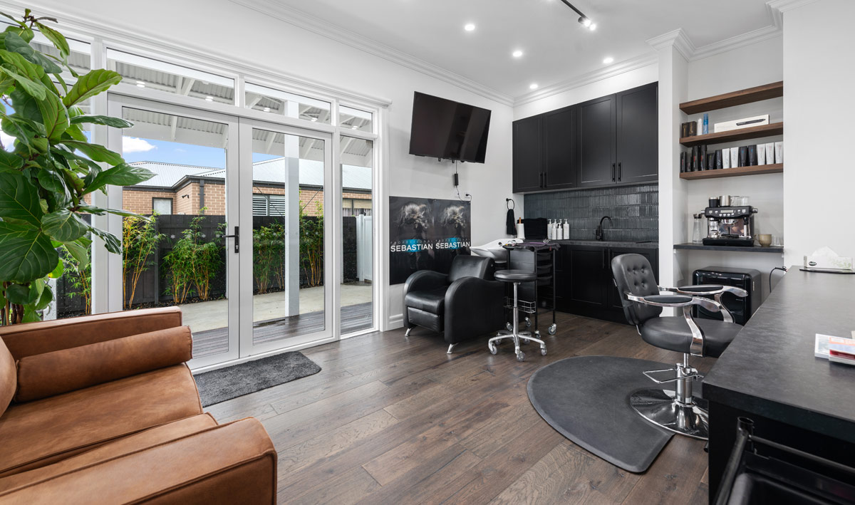 Work from Home space setup as a professional hair salon featuring timber floors, black benches and cabinets, black seating and large windows with lots of natural light