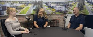 Two women and a man sitting at a table recording a podcast for Virtue Homes about the process of building a custom home.